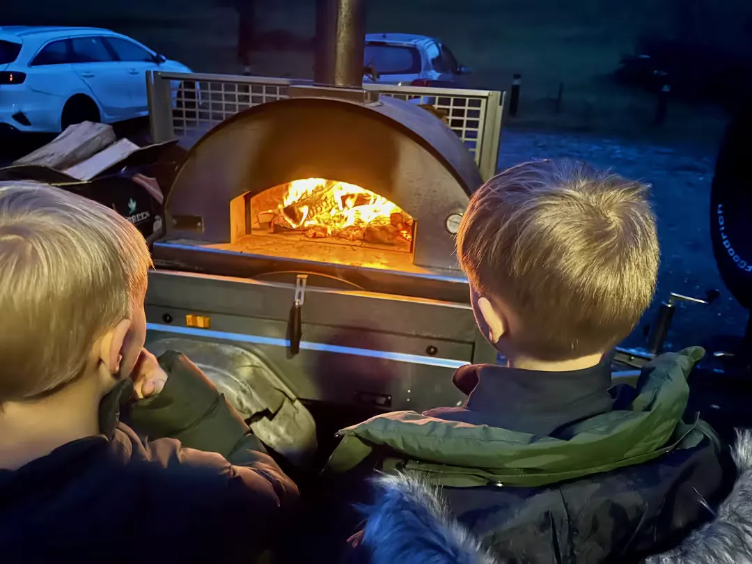 Spejdere der bager pizzer i brændefyret pizzaovn ved Bjørnholthytten